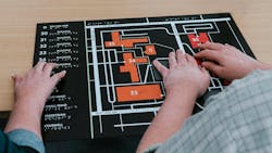 Two People Use Their Hands To Navigate A Campus Using A Tactile Map