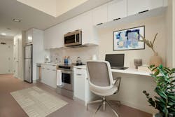 Micro-unit interior featuring a desk, compact appliances, and overhead storage Micro-unit interior featuring a desk, compact appliances, and overhead storage