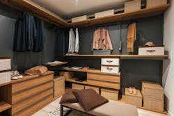 Modern walk in closet showing organized clothes, shoes, and accessories. Interior of a modern and spacious walk in closet featuring wooden shelves, drawers, and organized clothing, shoes, and accessories