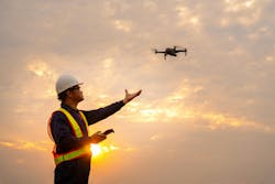 Surveyor deploying drone to view construction sites or check security at sunset.