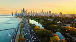 Chicago Cityscape at Sunset with Lakefront View. Aerial view of Chicago skyline at sunset, showing Lake Michigan shoreline, tree-lined parks, and a busy roadway along the waterfront