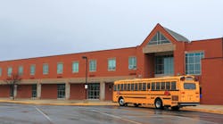 School Building with Bus. Red Brick School Building with Yellow School Bus at the front, ready for transporting students to home or drop off.