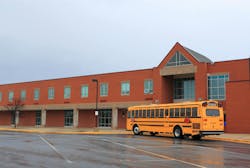 School Building with Bus. Red Brick School Building with Yellow School Bus at the front, ready for transporting students to home or drop off.