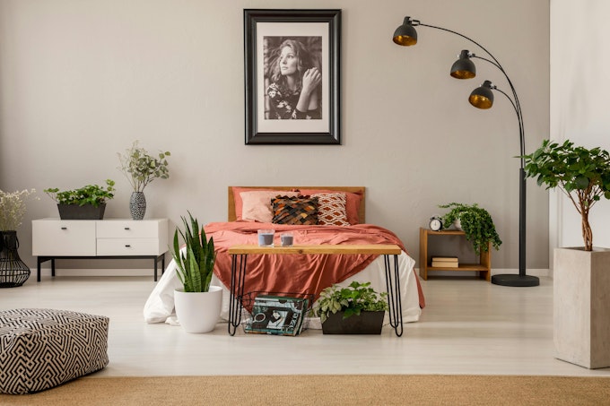 king size bed with rust color bedding in spacious bedroom interior of modern apartment, real photo