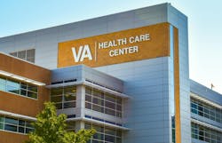 Veterans Administration Health Care Center. Horizontal, medium closeup of VA Health Care Center medical facilities exterior facade brand and logo signage adorning the modern architecture of the building in Charlotte, North Carolina with floors of reflective windows and a clear blue sky in the soft light of early morning.
